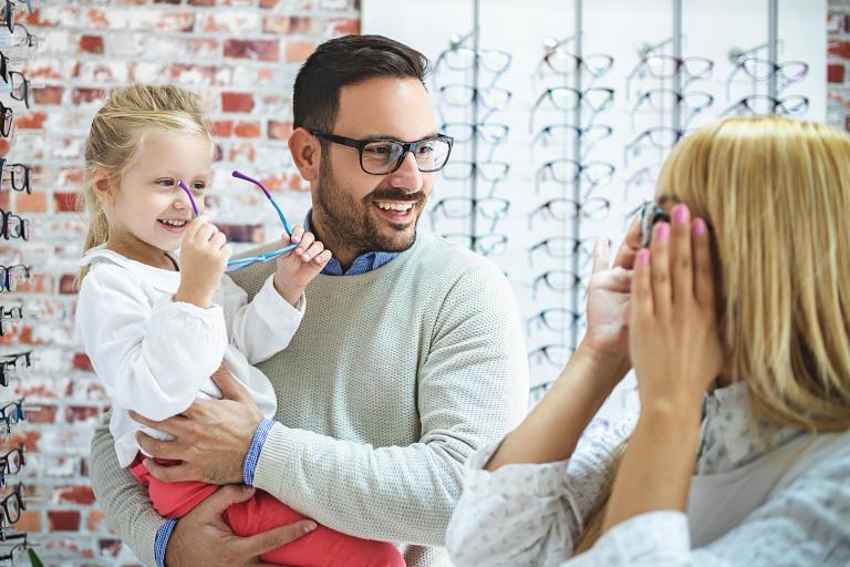 A family happily shopping for the top eyewear trends in a store. 