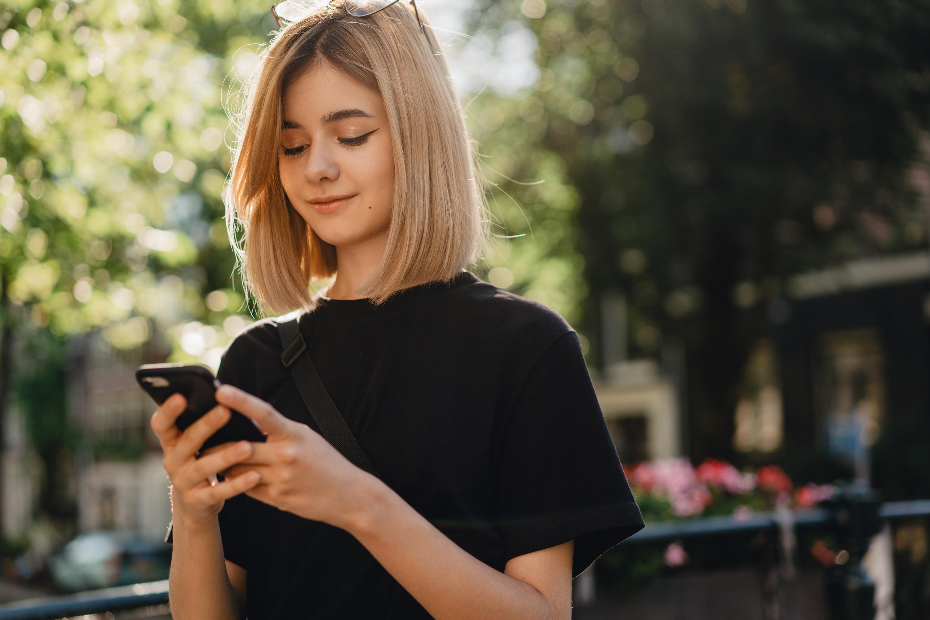A young woman enjoying a frictionless shopping experience while shopping from her phone. This shows how seamlessly Acima Leasing can integrate with your eCommerce storefront.